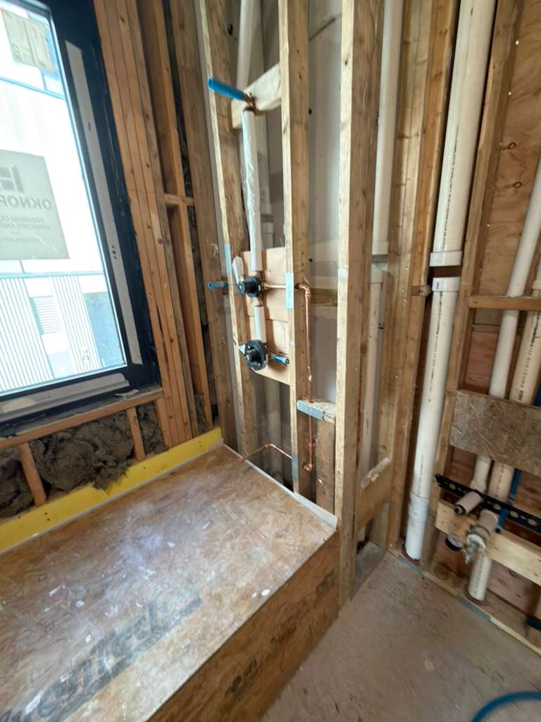 Bathroom rough plumbing installation with tub spout, handshower, and valve setup